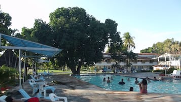 Área da piscina com espreguiçadeiras e um espaço coberto para relaxar.