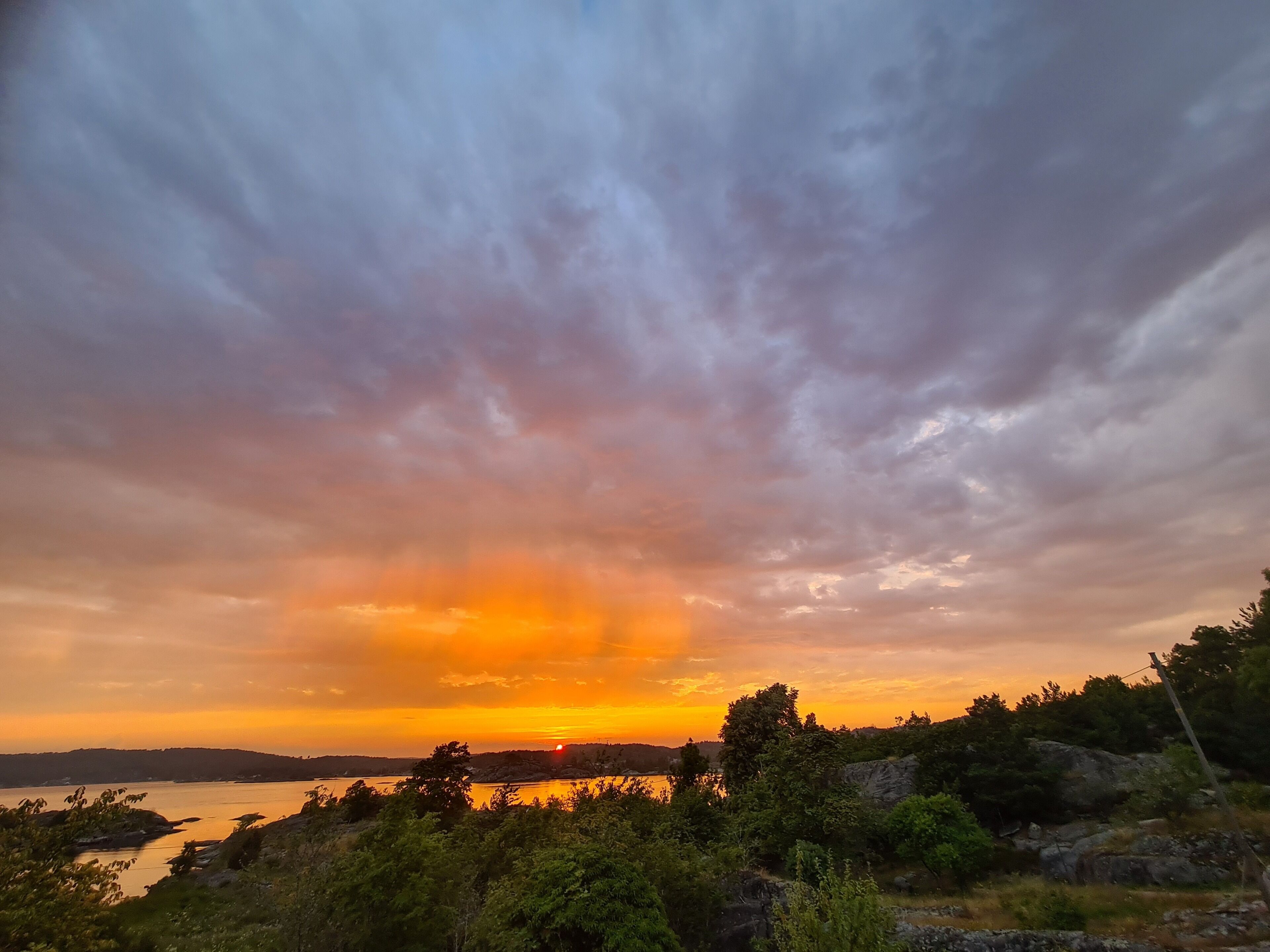 A sunset over a body of water with a forested area in the foreground.
