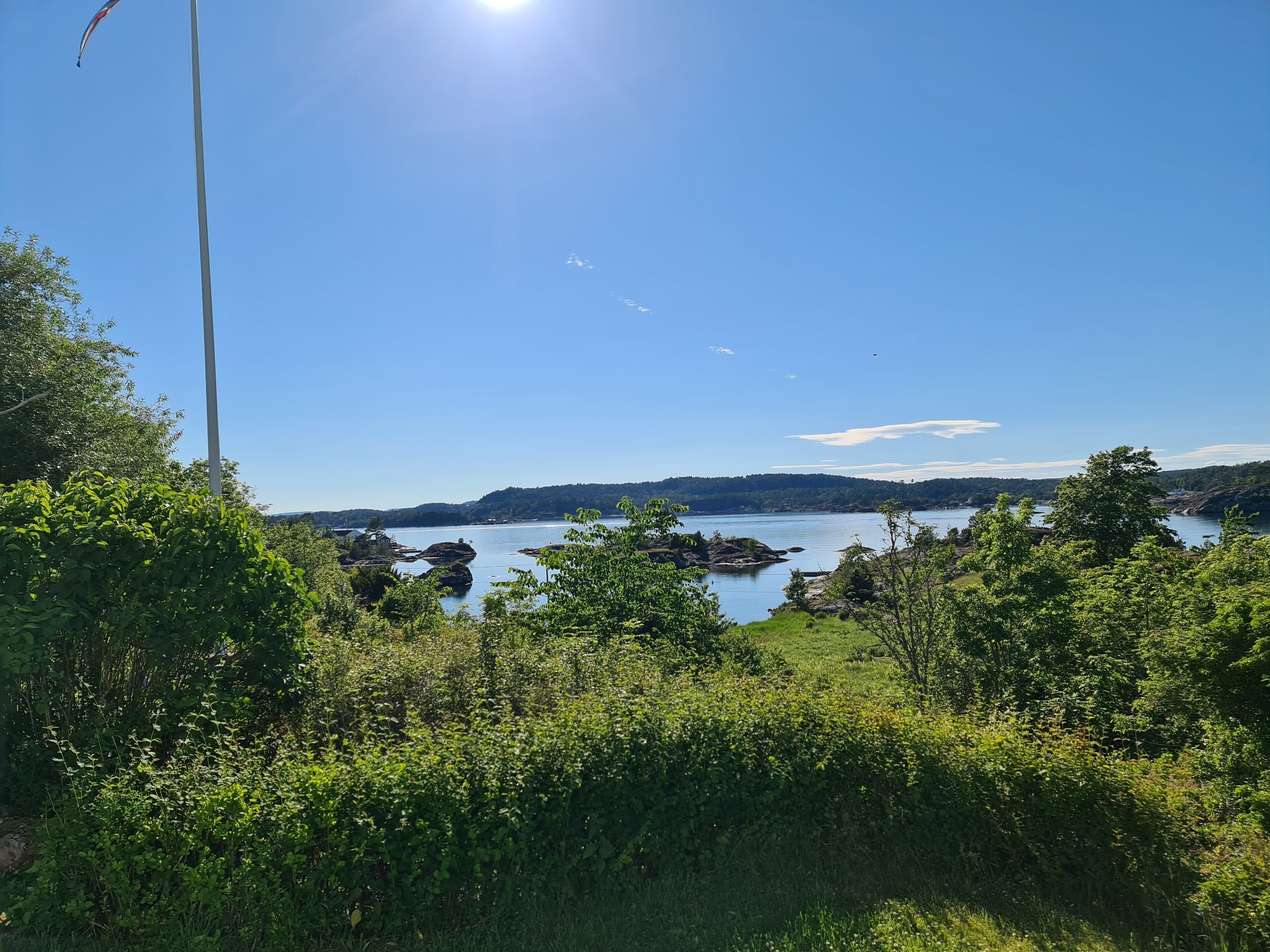 A clear view of a lake surrounded by lush greenery and rocky outcrops.