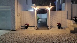 Una entrada con reja y un camino que lleva a una casa.