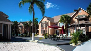 A hotel with multiple-story buildings, outdoor seating areas, and palm trees. - Sophisticated Retreat (Kissimmee)