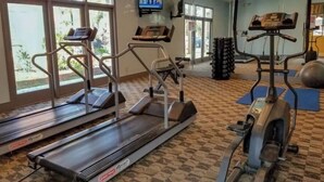 A gym with treadmills, elliptical machines, and exercise mats. - Sophisticated Retreat (Kissimmee)