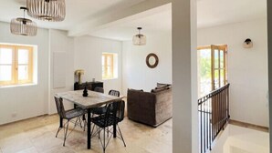 A spacious dining area with a large table and chairs, a sofa, and a staircase leading to another level.