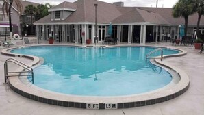 A swimming pool with a 5 ft depth marker, surrounded by a covered patio area with chairs and umbrellas. - Splash of Disney Color & Fun (Kissimmee)