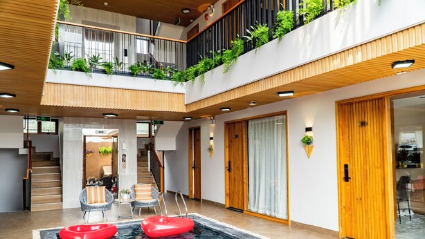 A modern indoor pool area with a wooden ceiling, a glass door leading to a balcony, and a red inflatable pool float. - SALA Serviced Apartment (Đà Nẵng)