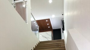 Un escalier en bois, avec des murs blancs et une rampe en verre.