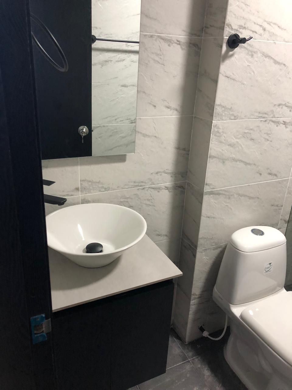Une salle de bain avec un lavabo blanc, des toilettes et un miroir.