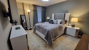 Une chambre d’hôtel moderne avec un grand lit, des tables de chevet, un bureau et un miroir.