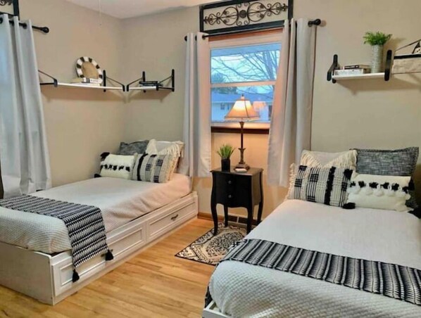 A bedroom with two beds, a small table, and a window with a view. - Fun Escape 1 - Starved Rock - Skydive- Game Room (Ottawa)