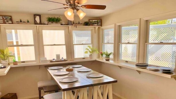A kitchen with a central island, white cabinetry, and a ceiling fan.