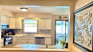 A modern kitchen with white cabinets, a central island, and a decorative wall piece.