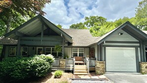 A two-story house with a front porch, a garage, and a stone foundation.