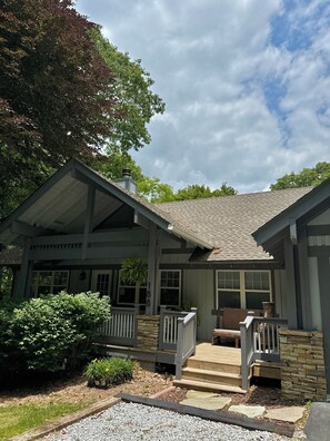 A two-story house with a porch, stone foundation, and a chimney. - Chestnut Cottage (Highlands)