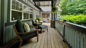 A covered porch with wooden furniture and a stone planter.
