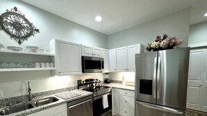 A modern kitchen with white cabinets, stainless steel appliances, and granite countertops.