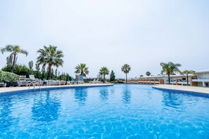 Une piscine avec des chaises longues et des palmiers.