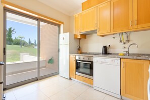 A kitchen with wooden cabinets, a refrigerator, an oven, a dishwasher, and a coffee maker.