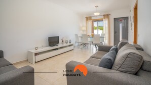 Un salon moderne comprenant un canapé, un téléviseur et un coin repas avec des chaises et une table.