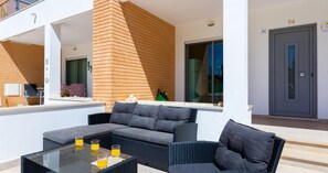 A modern outdoor living area with a glass-top table, cushioned seating, and a view of the building's exterior. - #154 V2 Vila Branca 54 by Home Holidays (Albufeira)