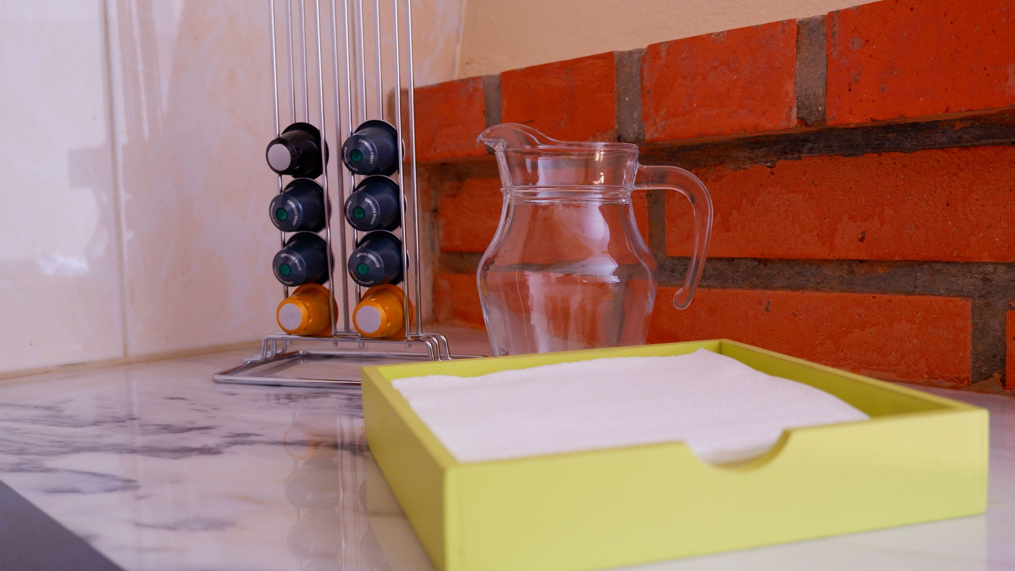 A kitchen counter with a coffee maker, a pitcher, and a box of napkins.