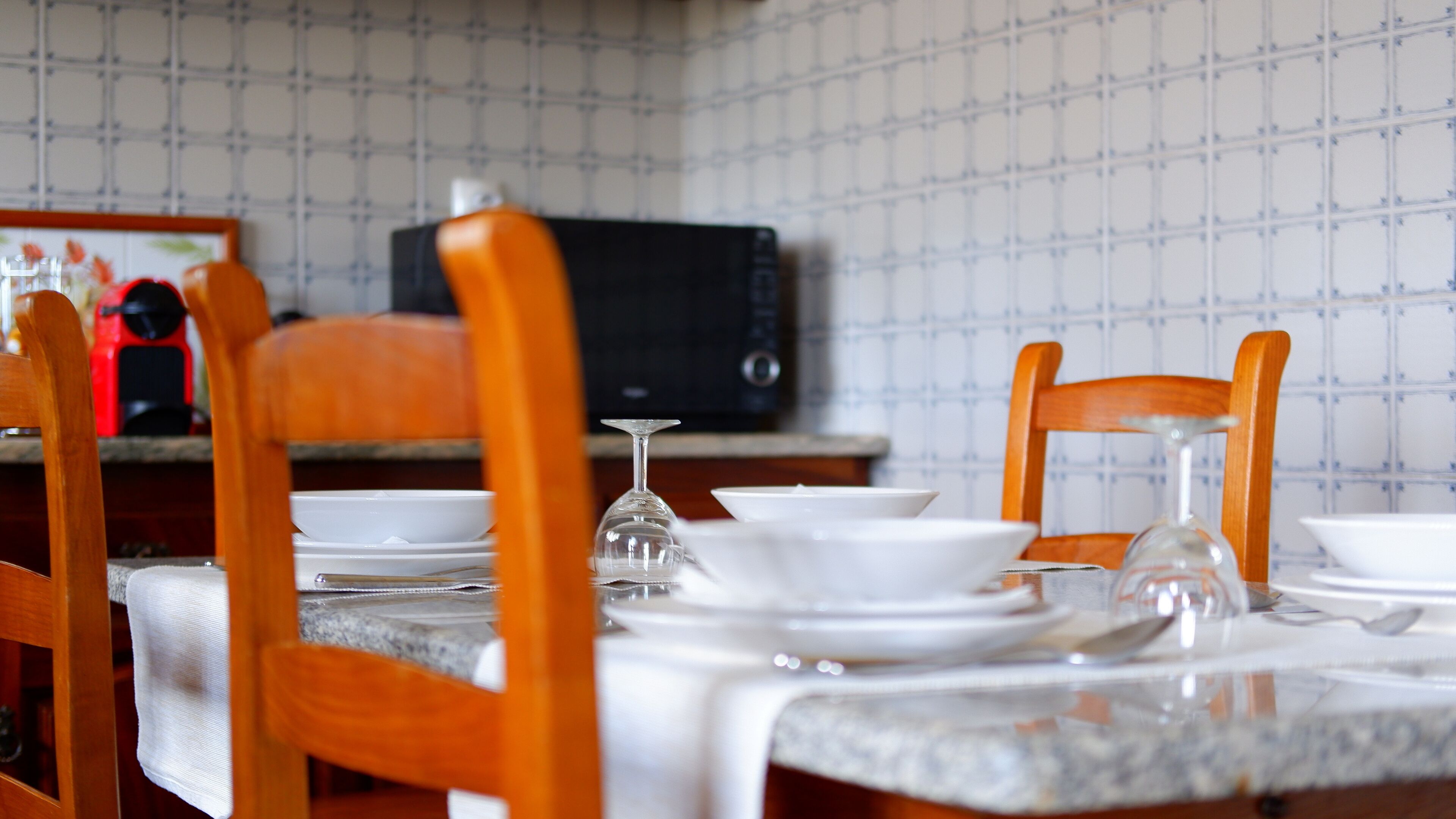 A dining table set with plates, a wine glass, and a microwave in the background.