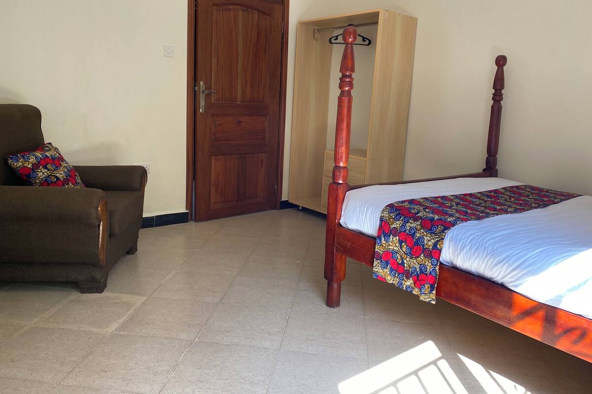A bedroom with a wooden bed, a chair, and a wardrobe.