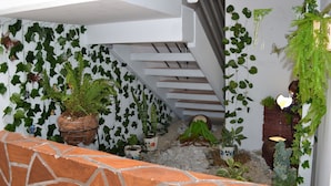 A narrow staircase with a white railing, surrounded by various potted plants and greenery. - Casa Confort (Pereira)