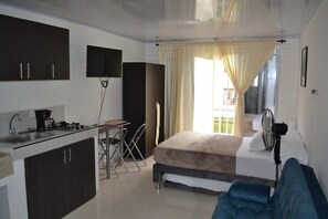 A compact hotel room with a kitchenette, a bed, a small table, and a chair. - Casa Confort (Pereira)