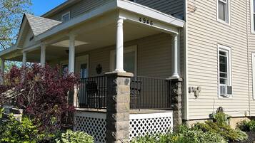 A two-story house with a covered porch, stone pillars, and a mailbox.