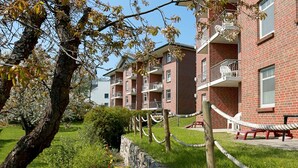 Edifici de maó amb múltiples balcons i una paret de pedra amb baranes de corda.