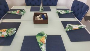 A conference table with a floral table runner, a brown box with decorative balls, and dark blue chairs around the table. - Tropical Paradise (Bridgetown)