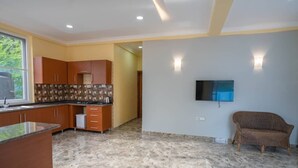 Una cocina moderna con armarios de madera, piso de mármol y televisor de pantalla plana montado en la pared.