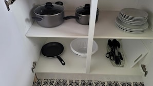 Una repisa de cocina con utensilios de cocina, incluyendo ollas, sartenes y un colador.