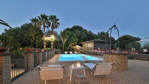 A pool area with a brick patio, lounge chairs, and a small table with candles. - Villa Biddizza 10, Emma Villas (Acireale)