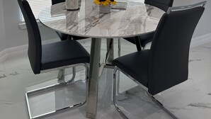 A round marble table with four black chairs, a vase with yellow flowers, and a white tray. - Newly built home near SWIFlorida airport  (Lehigh Acres)