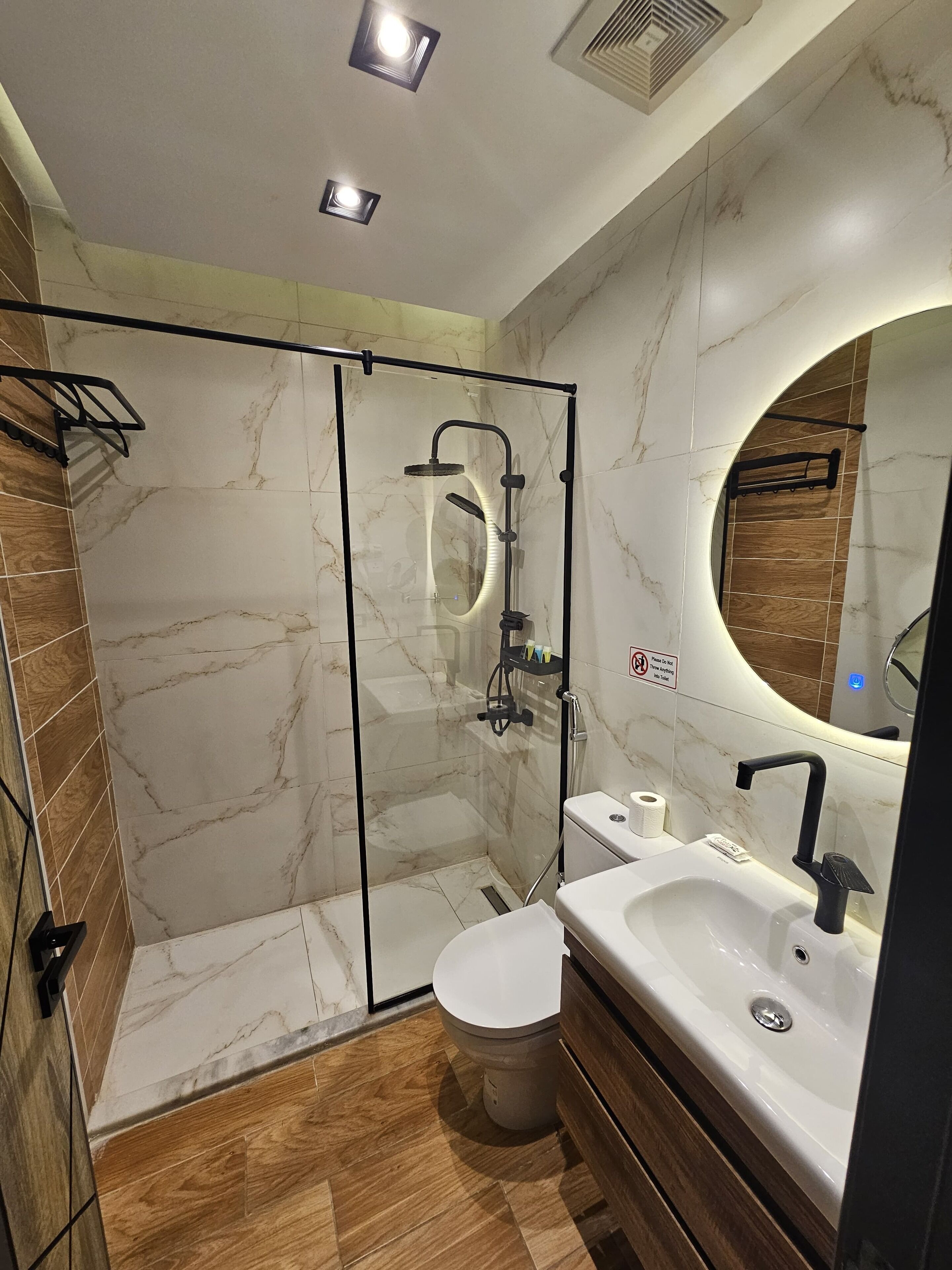 A modern bathroom with a glass-enclosed shower, a toilet, and a sink with a mirror.