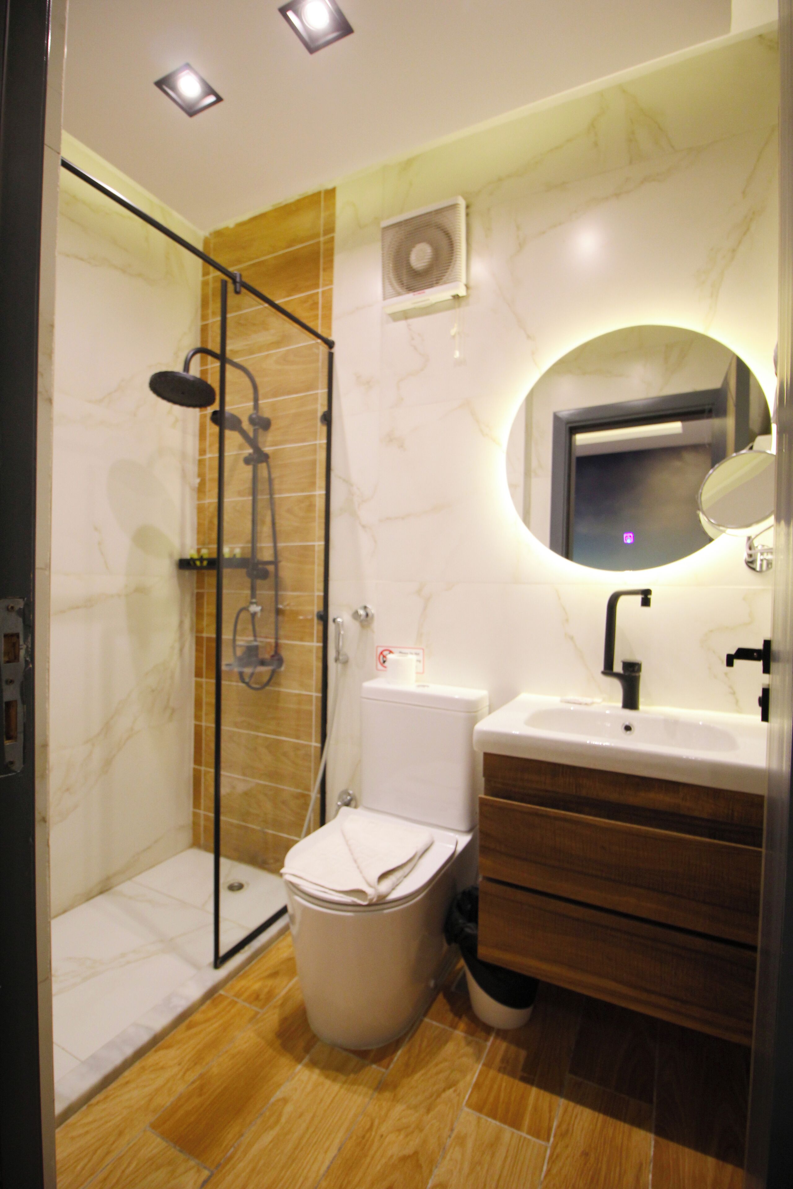 Un baño moderno con ducha de vidrio, inodoro, lavabo y tocador con cajones.