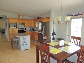 A spacious kitchen with wooden cabinets, a central island, and a dining area with a table set for four.