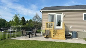 A small house with a patio area featuring a table and chairs, a wooden deck, and a fenced yard. - Cute 3BR/2BA home located in the Village of Clayton with dock rental available (Clayton)