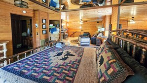 Une chambre confortable, aménagée dans le style d’un chalet, avec un grand lit, un plafond en bois et une esthétique rustique.