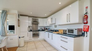 A modern kitchen with white cabinets, a microwave, and a sink. - Beachcomber (Penzance)