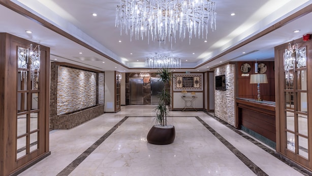 A spacious lobby with a marble floor, a central potted plant, and a modern chandelier. - Ain Benian (Algiers)