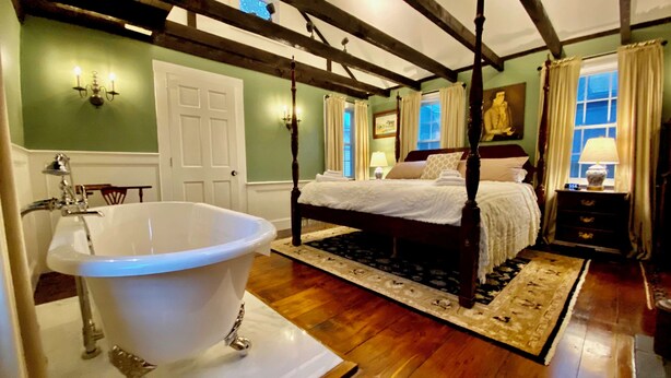 A bedroom with a large clawfoot bathtub, a four-poster bed, and a wooden ceiling. - Silsbee's by Daniels House (Salem)