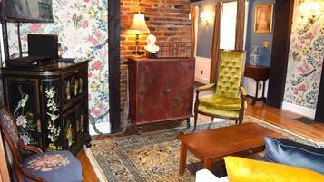 A cozy living room with a wooden coffee table, a green armchair, and a floral-patterned sofa.