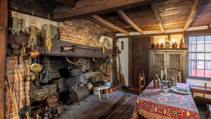 A rustic kitchen with exposed brick walls, wooden beams, and various cooking utensils. - Silsbee's by Daniels House (Salem)