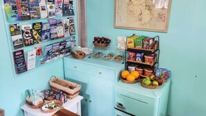 A room with a light blue wall, a map, a shelf with snacks, a basket of bread, and a drawer with a white cabinet. -  Lighthouse Cabins Maine (Bass Harbor)
