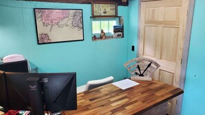 A room with a wooden desk, a computer monitor, a framed map, and a wooden door. -  Lighthouse Cabins Maine (Bass Harbor)
