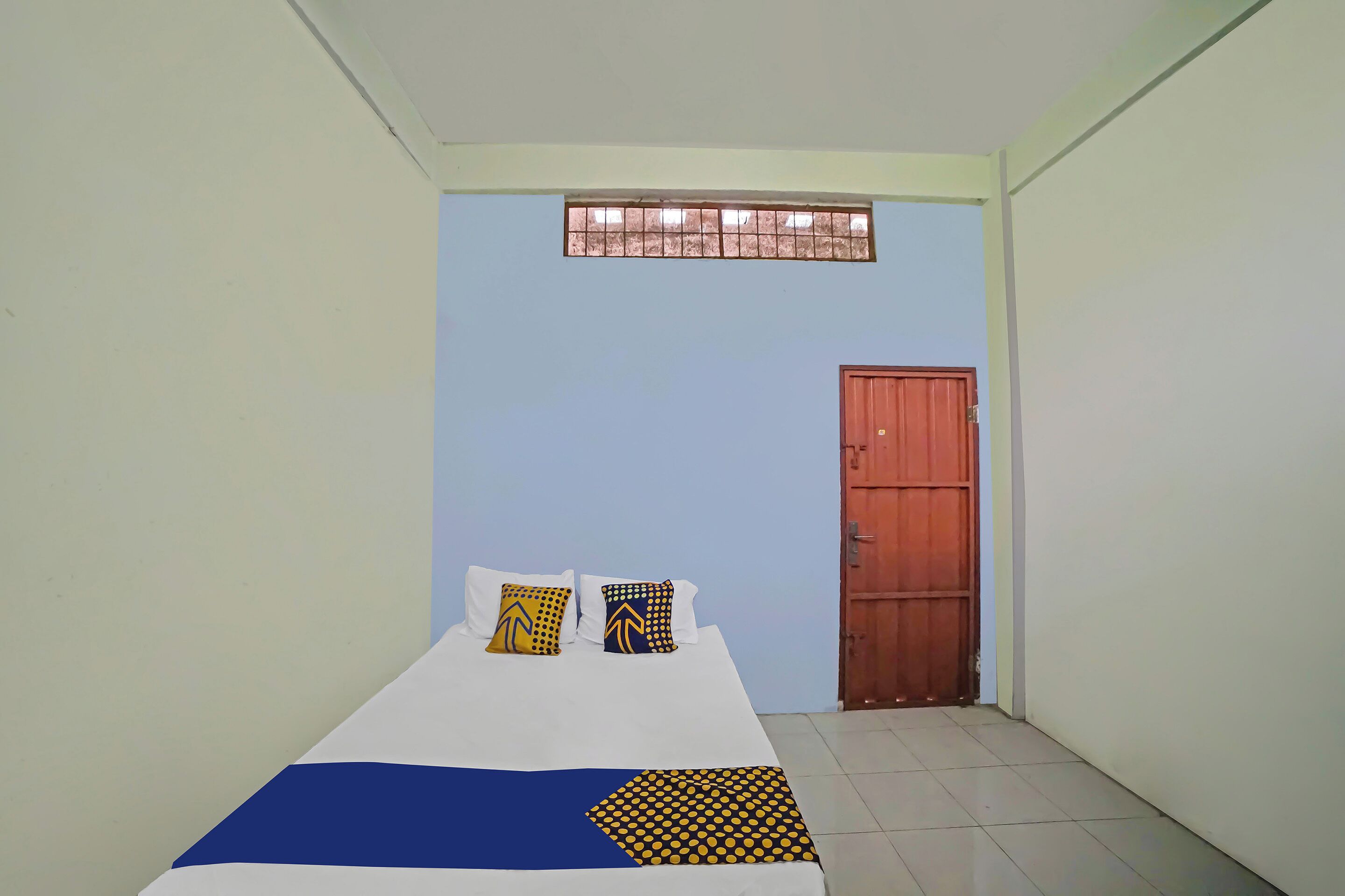A bedroom with a bed, pillows, a window, and a door.