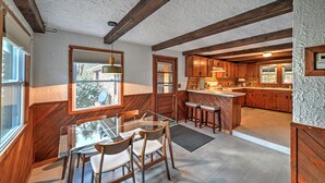 Una cucina moderna con travi in legno, un tavolo da pranzo in vetro e vista sull'esterno.