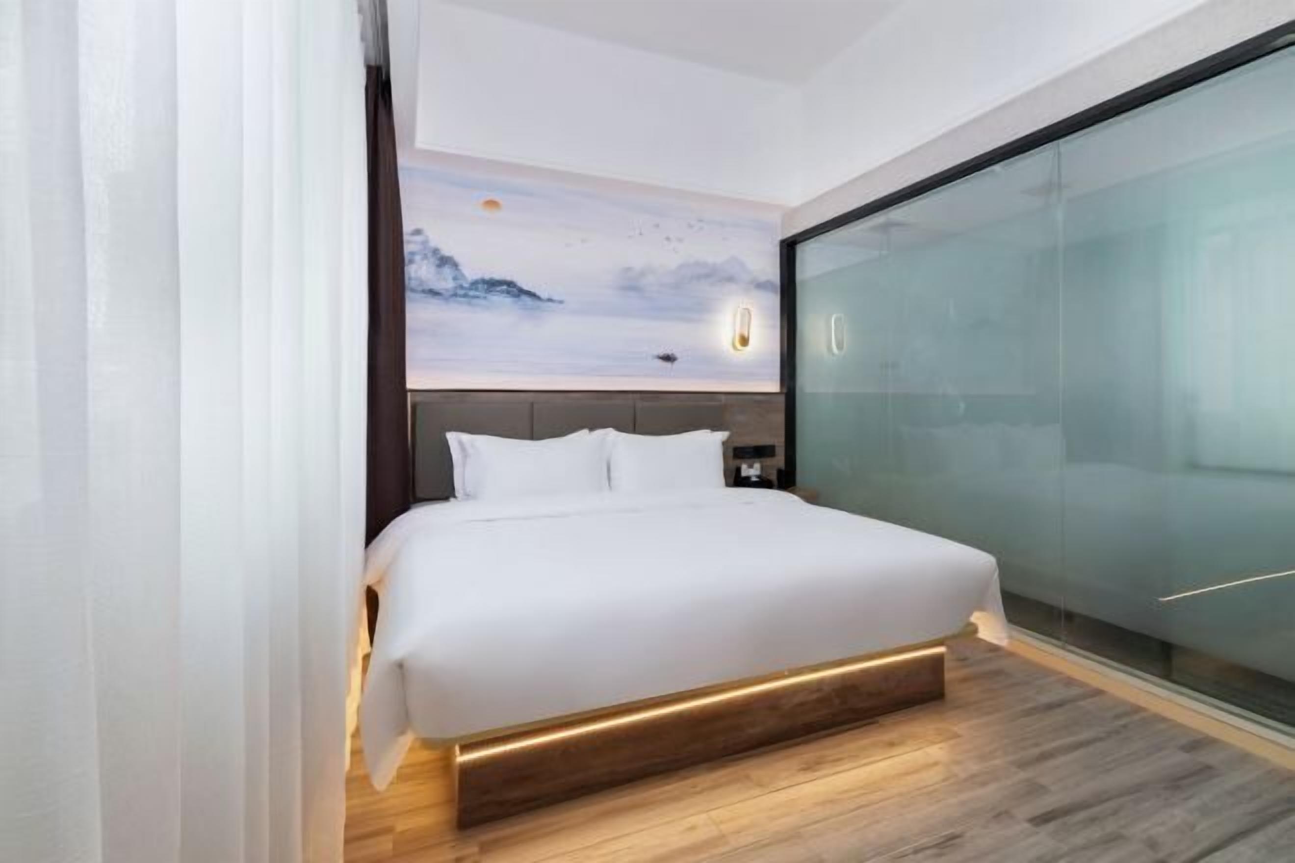 A modern bedroom with a large bed, a glass partition wall, and a mural of a mountain scene on the ceiling.